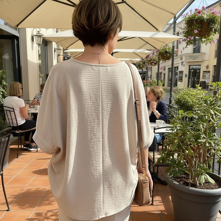 Chic Collective sand beige woven top with puff half sleeves and V-neck, worn by a woman outdoors.