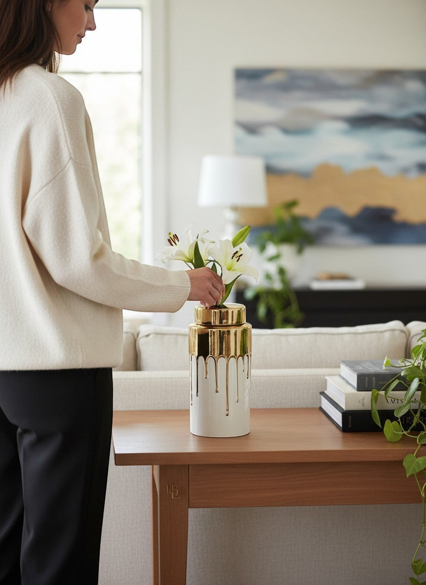Chic Collective white ceramic jar with gold lid and dripping gold accents, holding white lilies.