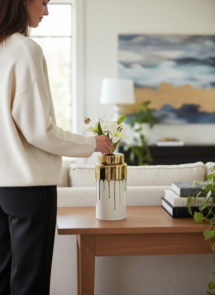 Chic Collective white ceramic jar with gold lid and dripping gold accents, holding white lilies.