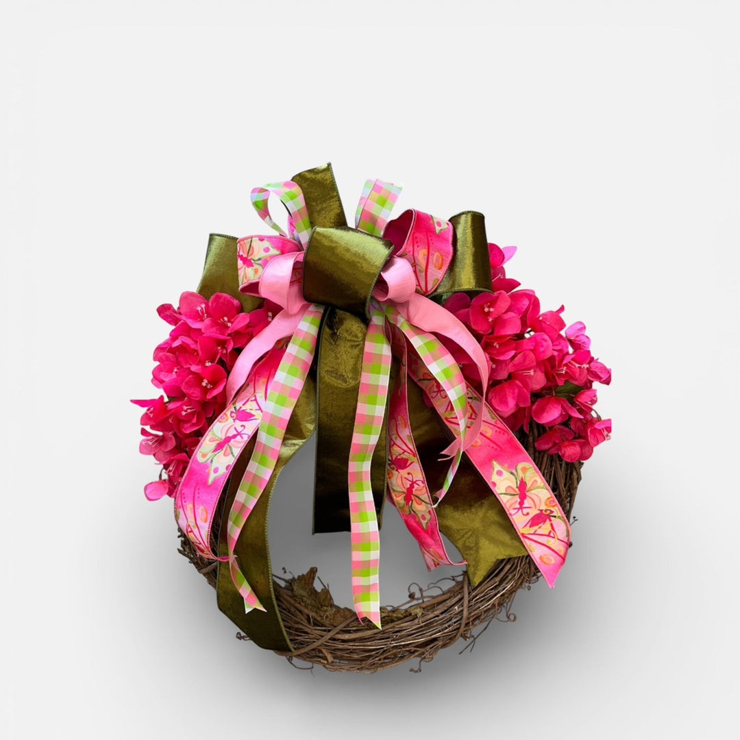 Chic Collective 24-inch grapevine wreath with vibrant pink flowers and a large bow featuring pink, green, and butterfly patterned ribbons.